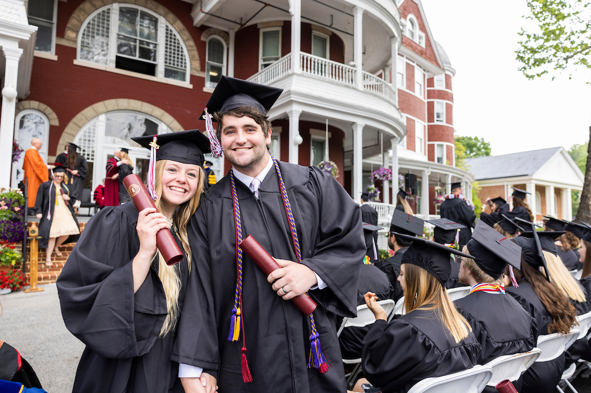 Two married students hold hands at graduation after receiving their diplomas