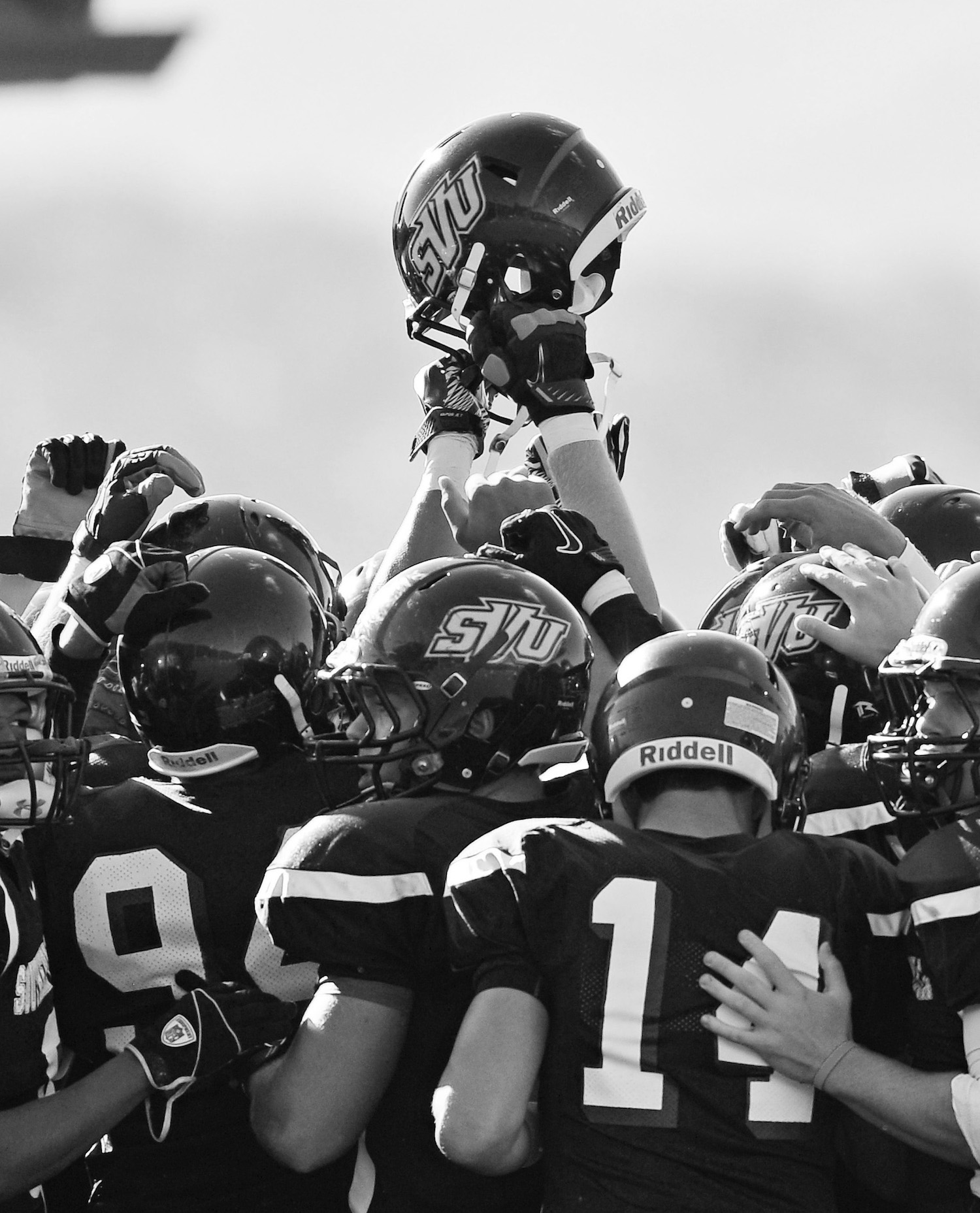 football teammates hold up an SVU helmet after a win in 2016