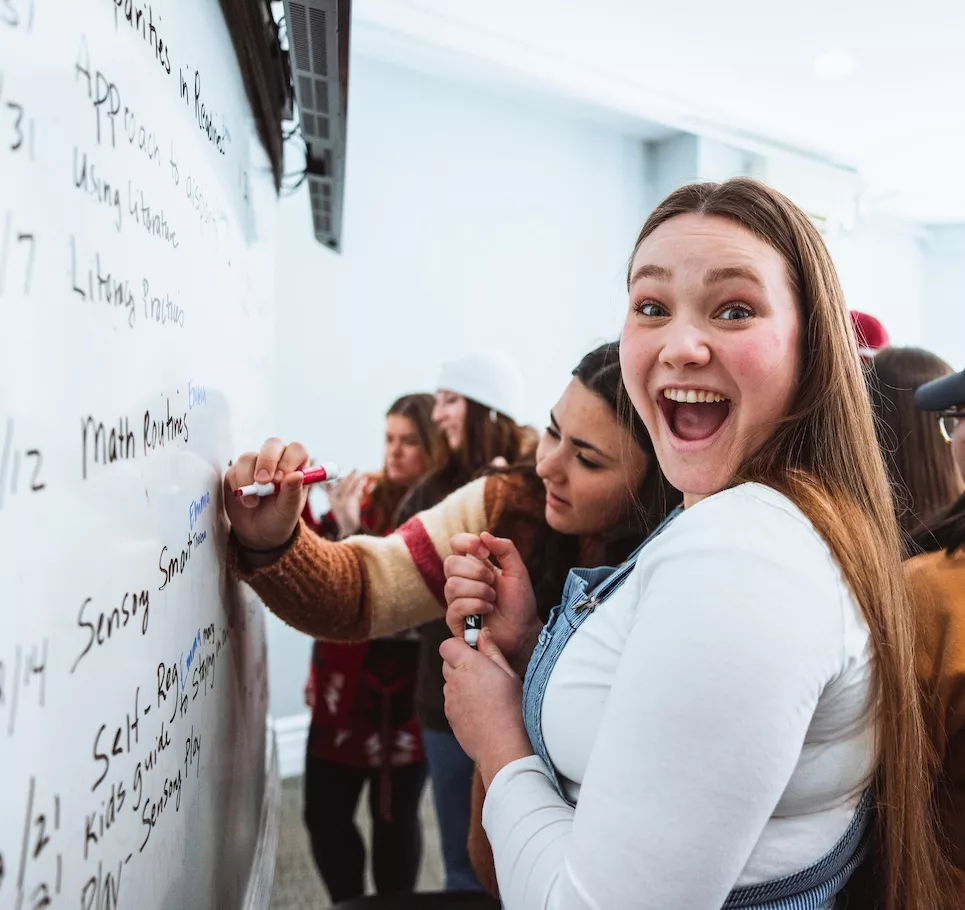 Students writing on a whiteboard.