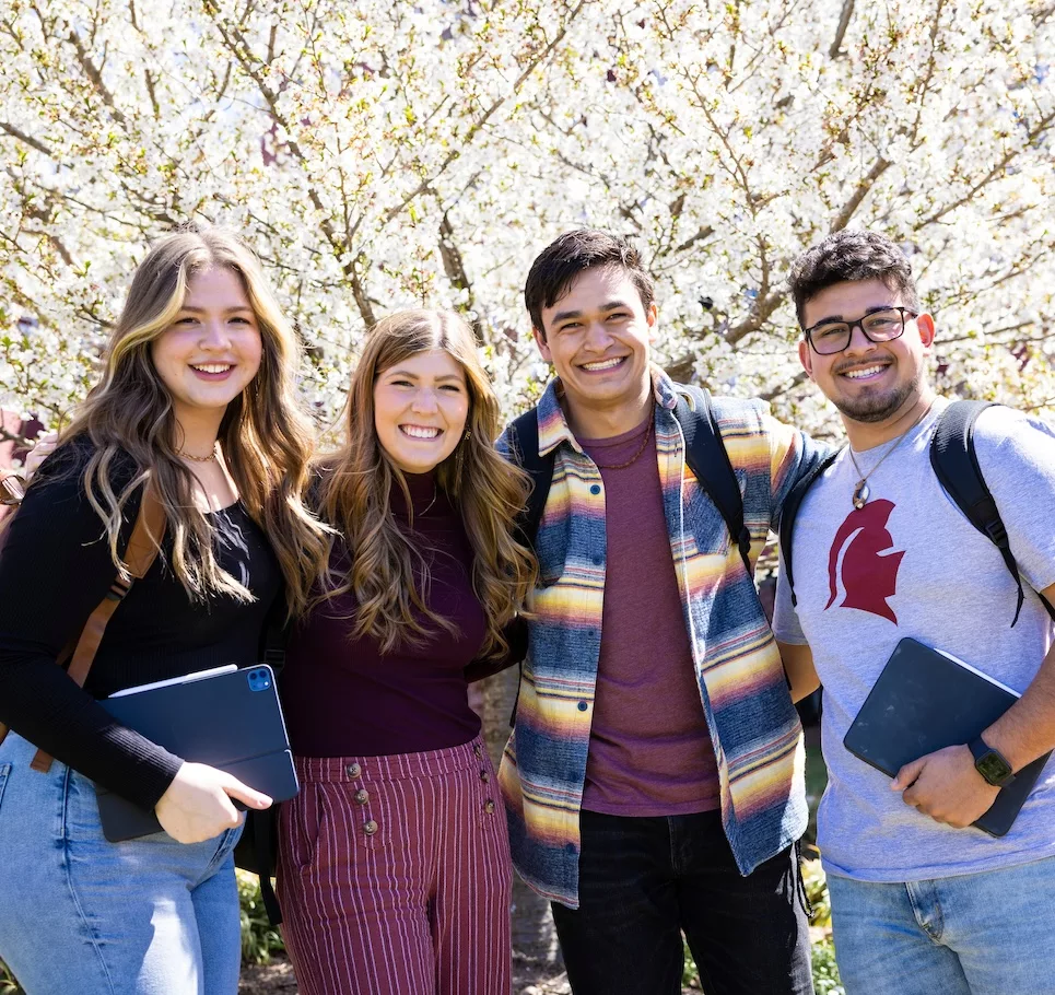 Four Southern Virginia University students in front of a white flowering tree.