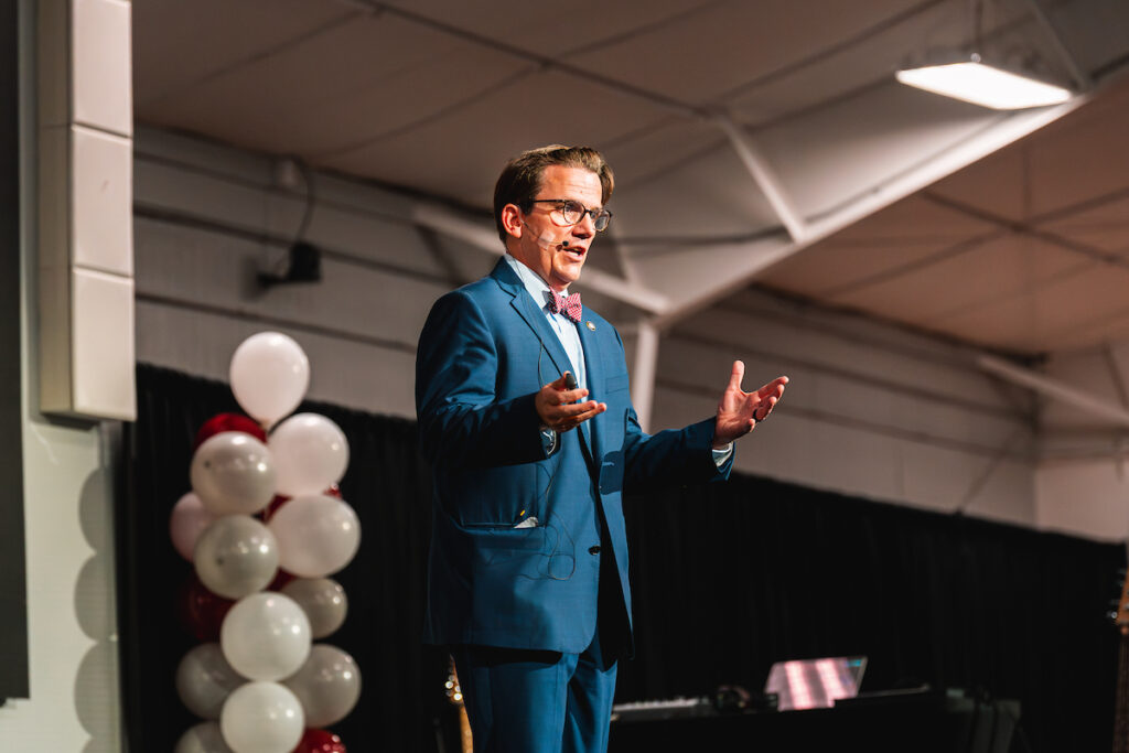 A man in a suit speaks on a stage